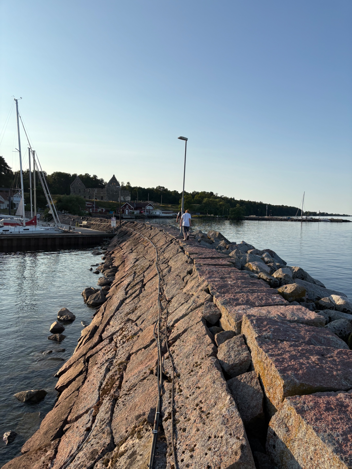Klippig pir vid hamn i sommarkväll